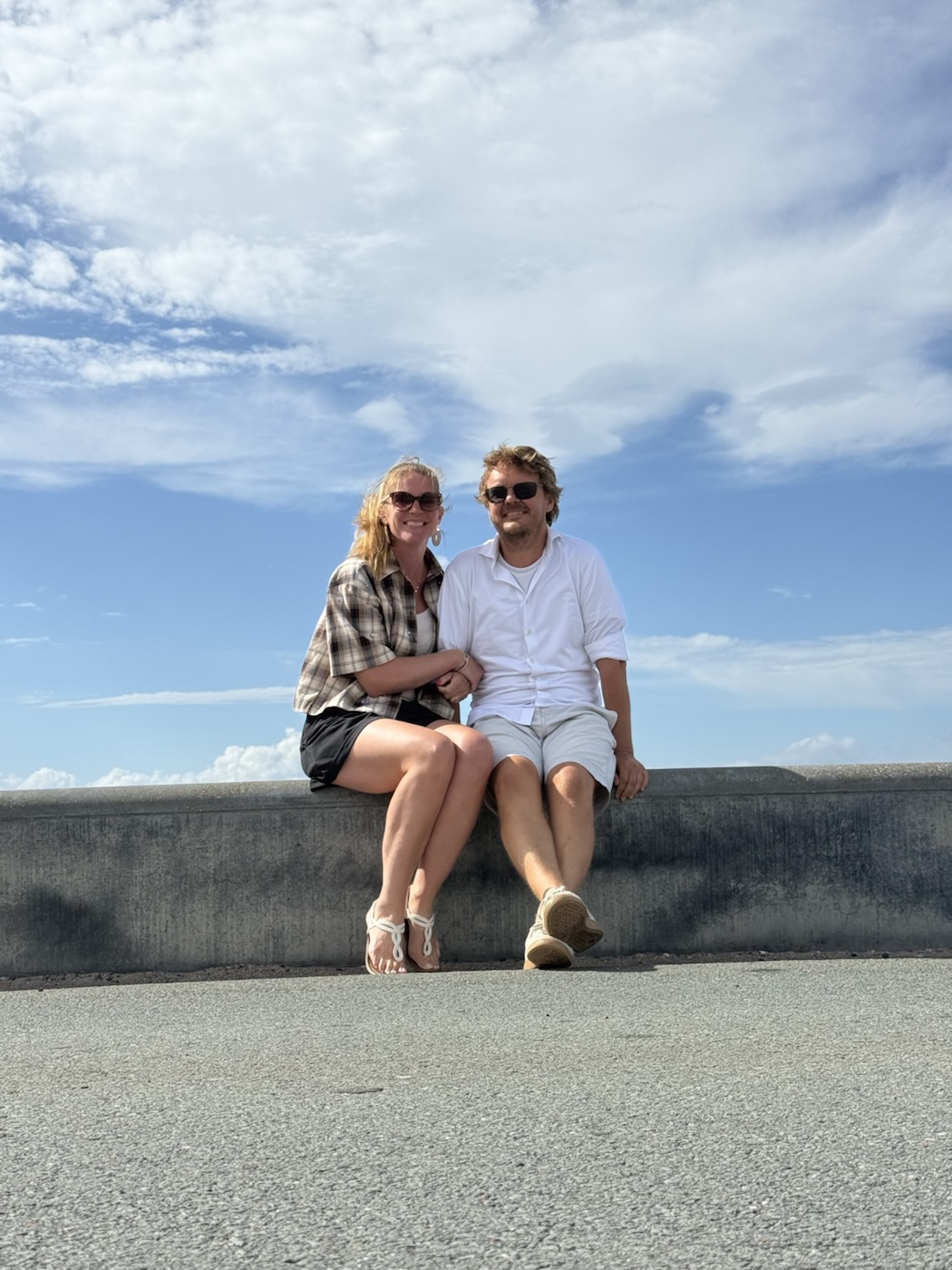 Addy en Evelien op een muurtje onder een blauwe lucht