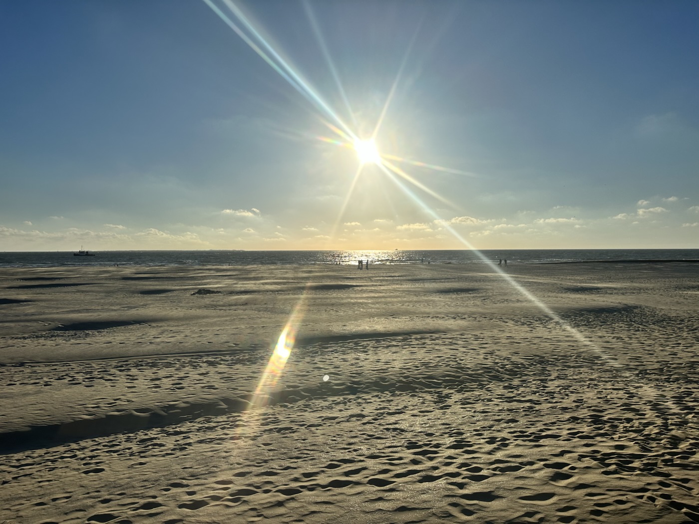 Zon boven het strand en de zee, met voetstappen in het zand