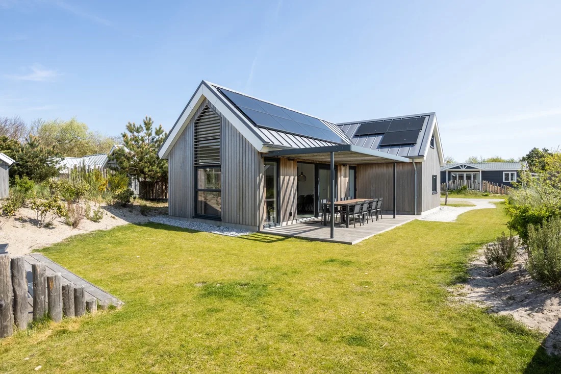 Een houten vakantiehuisje met terras en tuin in de duinen