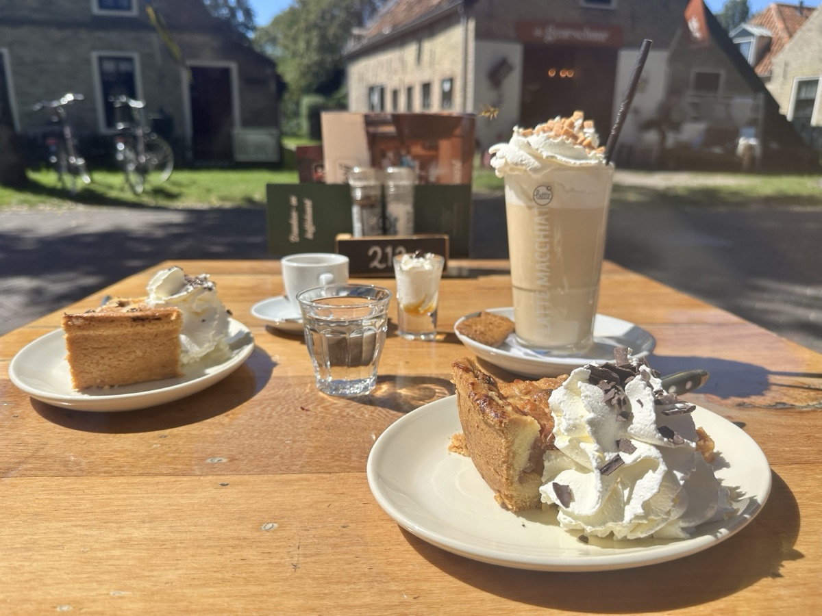 Taart met slagroom en een latte macchiato op een zonnig terras in het dorp