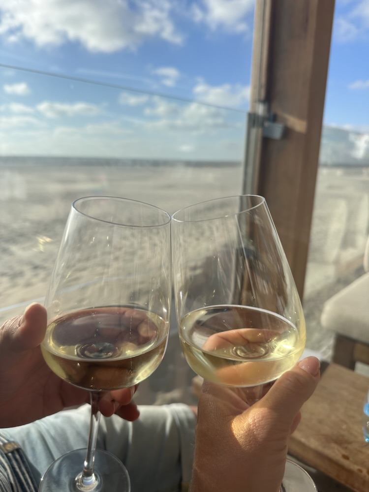 Proosten met witte wijn op een terras aan het strand