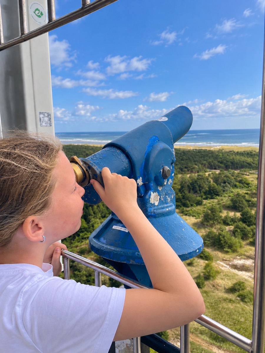 Kijken door de verrekijker boven in de vuurtoren, met uitzicht over de duinen en de zee